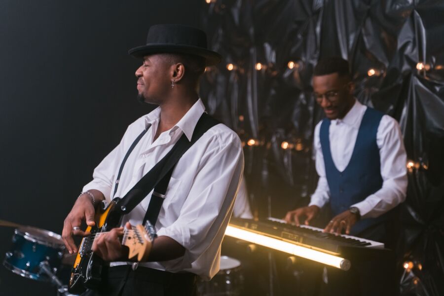 A guitarist and a keyboard player under stage lights