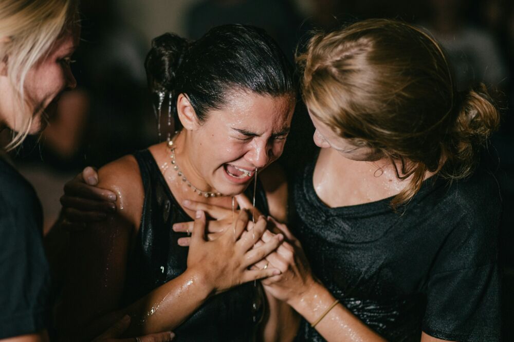 A baptism, her eyes closed and hands clasped, the emotion of the frame